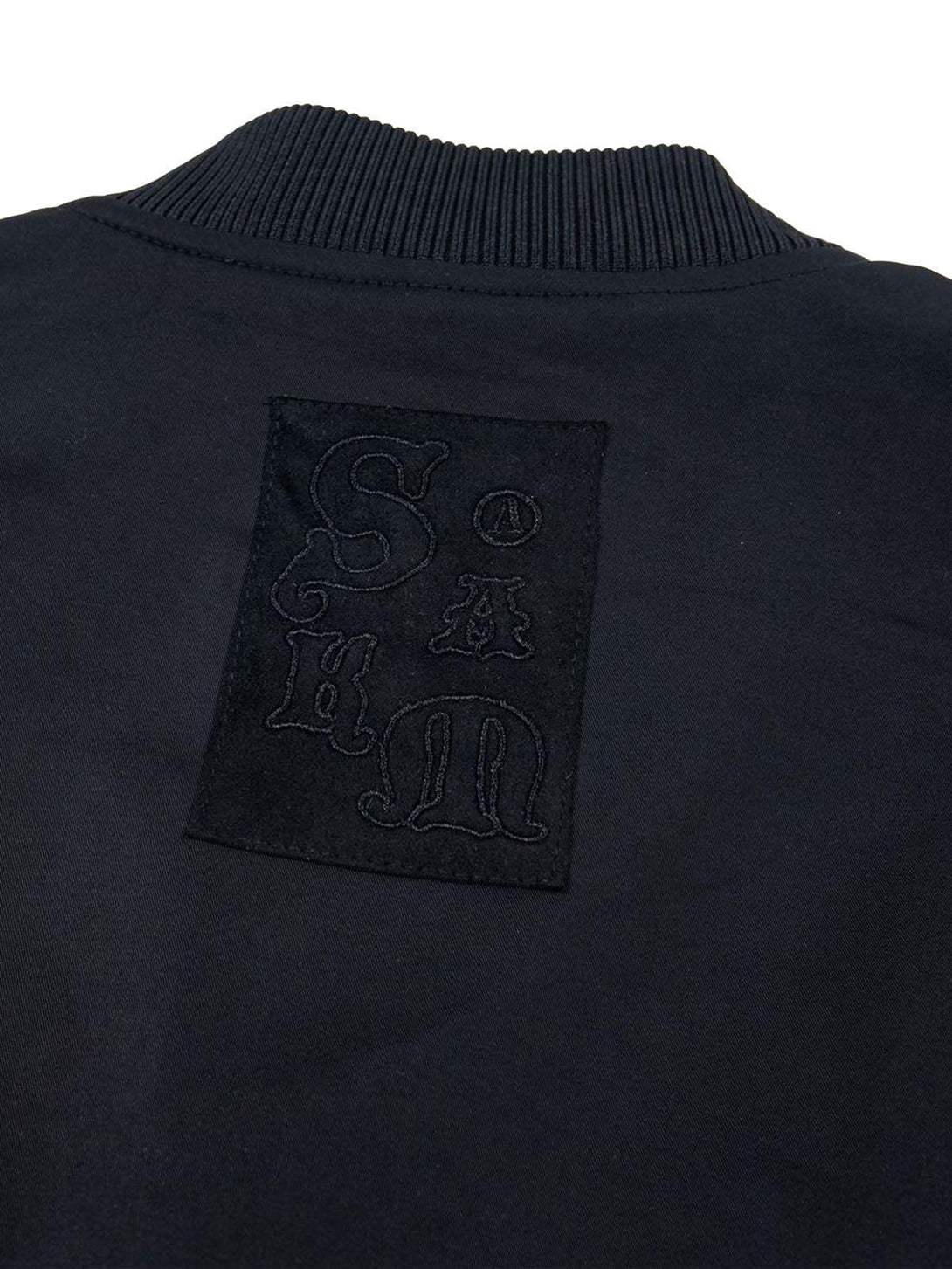 A detailed look at the unique embroidery on TALISHKO's retro deconstructed bomber jacket.