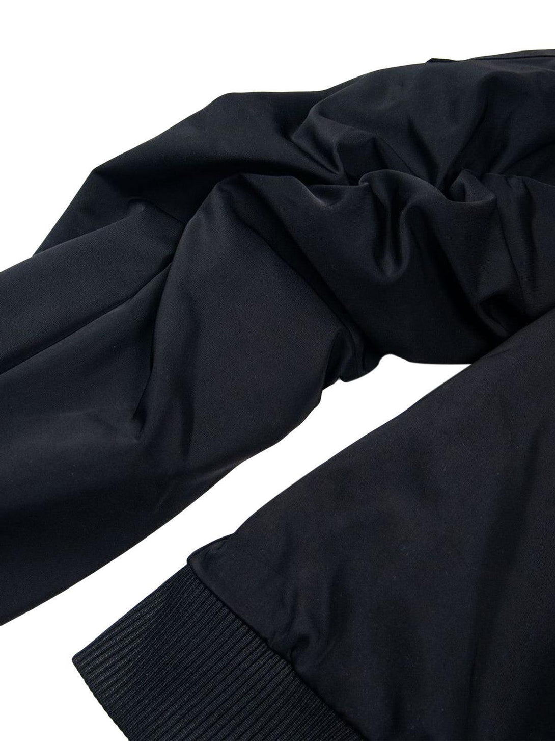 A detailed view of the black fabric and ribbed cuff on TALISHKO's retro deconstructed bomber jacket.