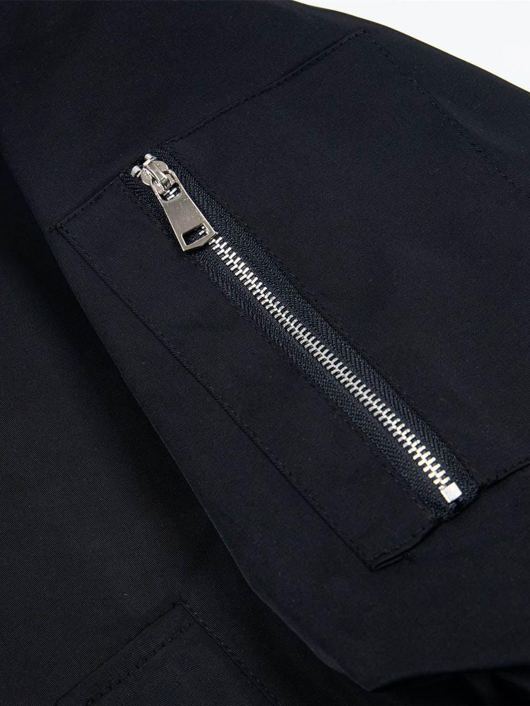 A close-up of TALISHKO's retro deconstructed bomber jacket pocket, featuring a sleek zipper.