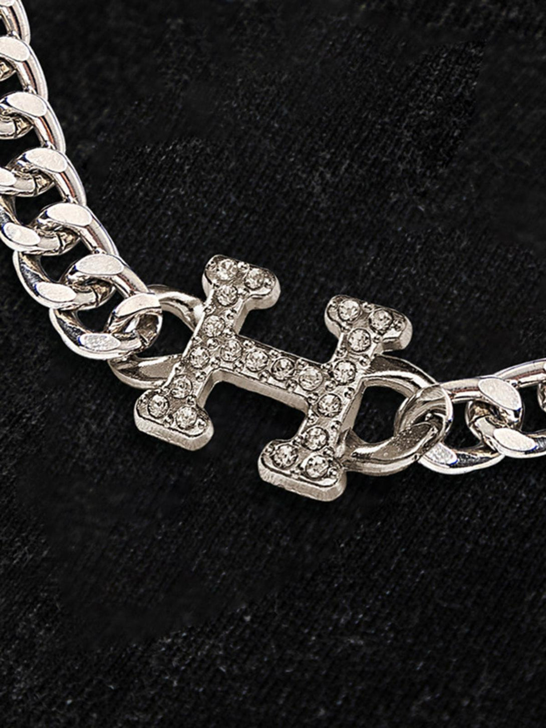 A close-up of TALISHKO's chain detail with a sparkling 'H' pendant, adding elegance.