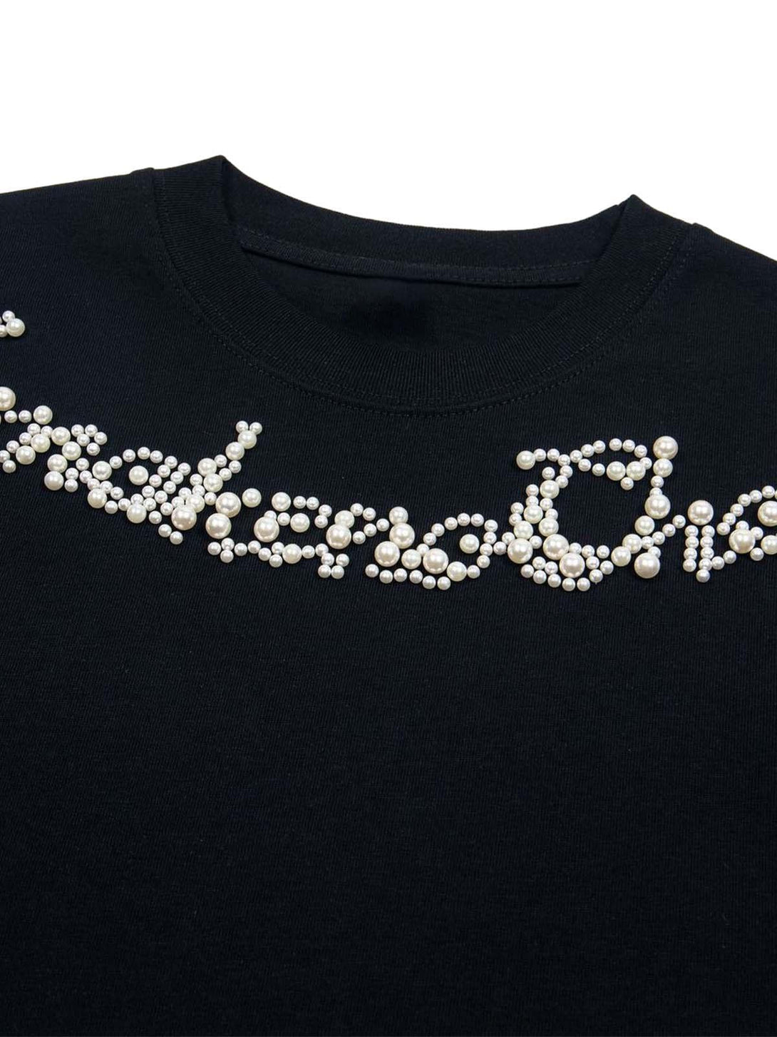 Close-up of a black T-shirt by TALISHKO with intricate pearl beaded lettering detail.
