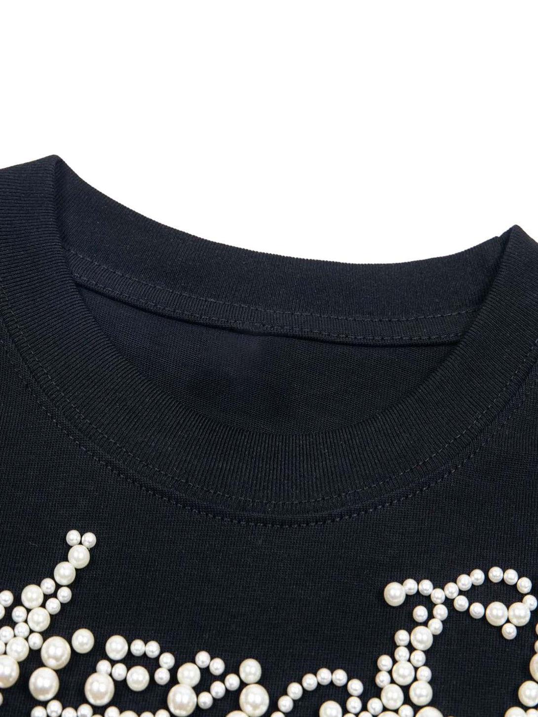 Intricate look at pearl beaded details on a black T-shirt collar by TALISHKO.