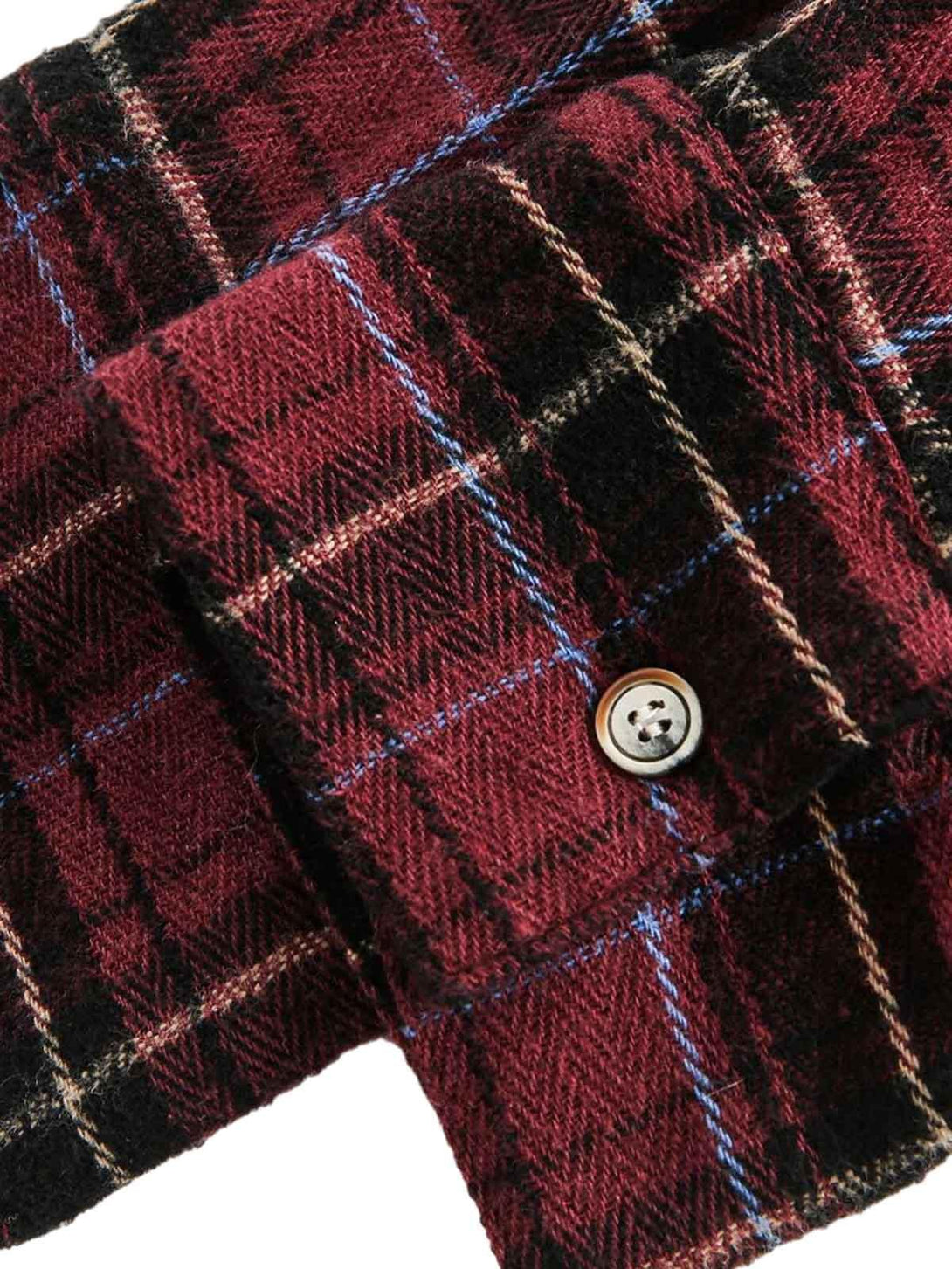 Intricate look at TALISHKO's retro plaid shirt cuff, highlighting the detailed button design.