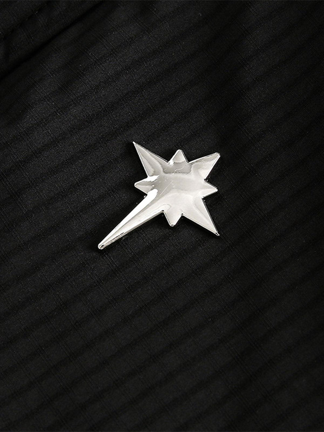 A close-up of a star-shaped silver brooch on the TALISHKO fleece bomber jacket, highlighting detail.