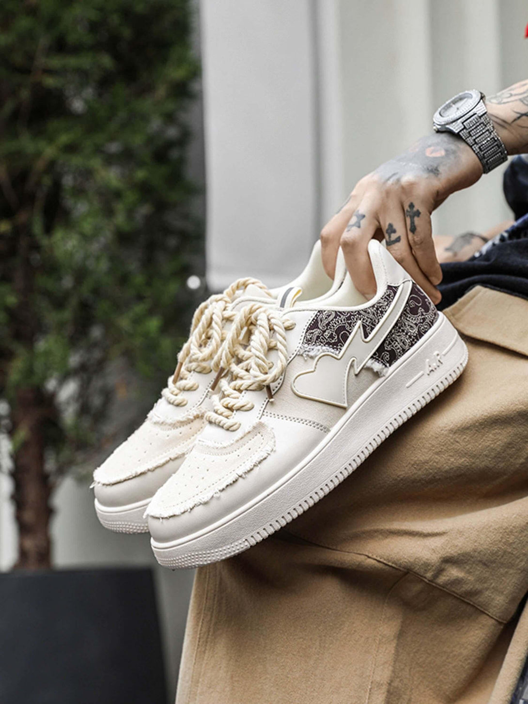 TALISHKO casual skate shoes in cream, featuring heart and pattern details, held by a tattooed hand.