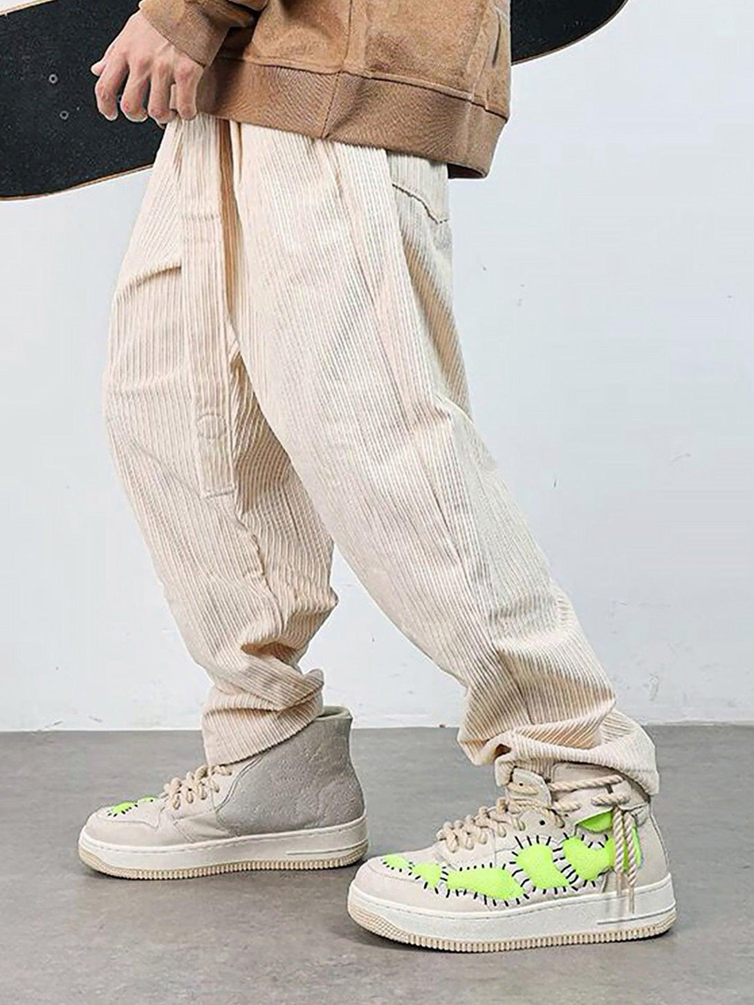 TALISHKO retro high-top sneakers with neon green accents, worn with casual ribbed pants.