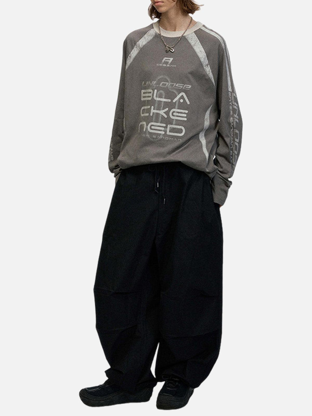 Model in oversized retro long-sleeve T-shirt by TALISHKO, paired with wide black pants.