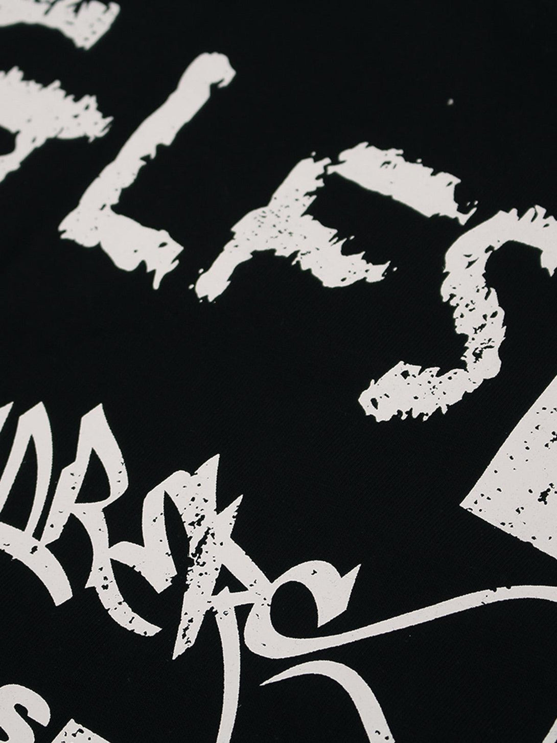 Intricate look at the distressed letter design on the TALISHKO graphic T-shirt.