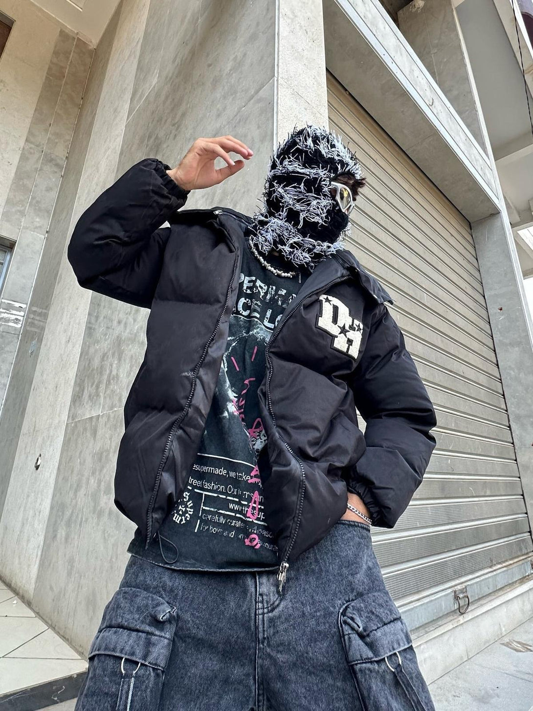 Model wearing TALISHKO down jacket with retro letter print, paired with dark cargo pants.