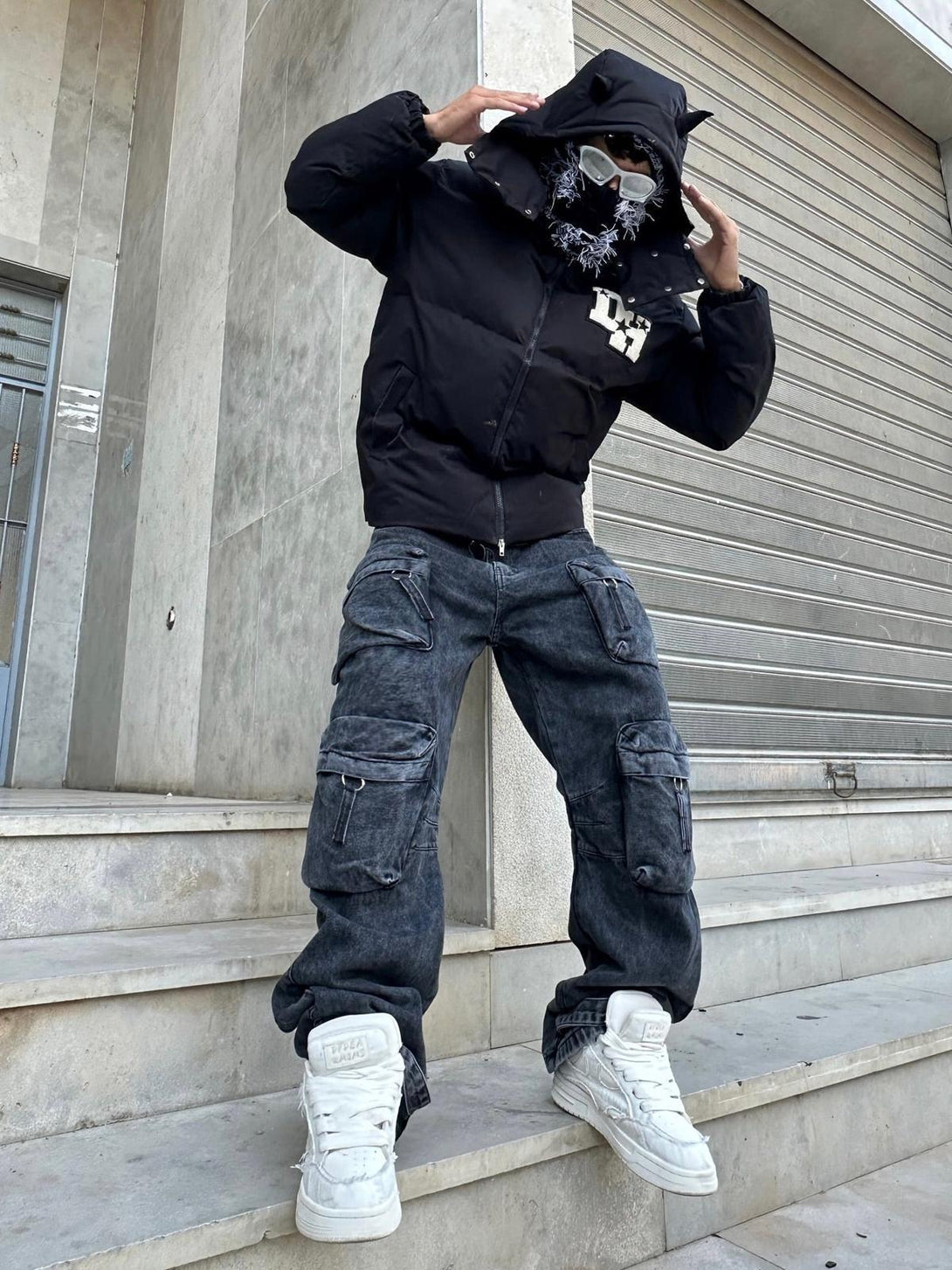 Model wearing TALISHKO retro letter print down jacket with cargo pants and sneakers on steps.
