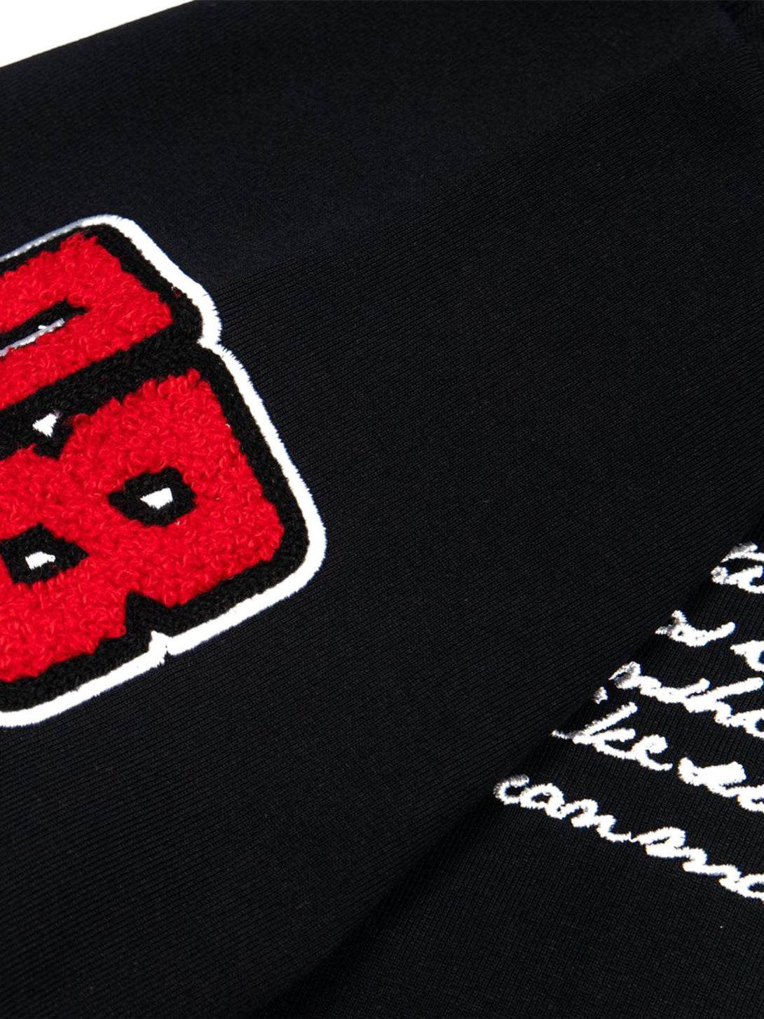 Detailed fabric and stitching on TALISHKO T-shirt, featuring bold red retro motorcycle patches.