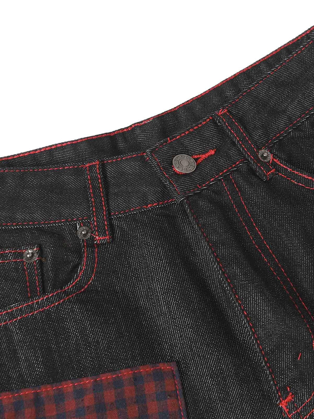 A detailed view of TALISHKO retro patchwork baggy jeans highlighting red stitching and texture.