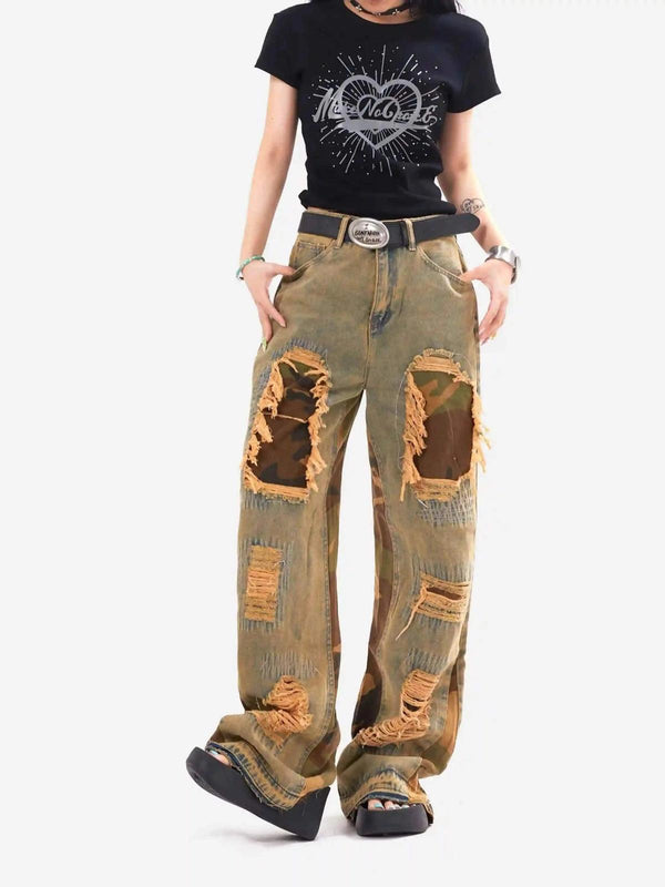 Model wearing distressed patchwork camouflage flared jeans by TALISHKO with a graphic tee.