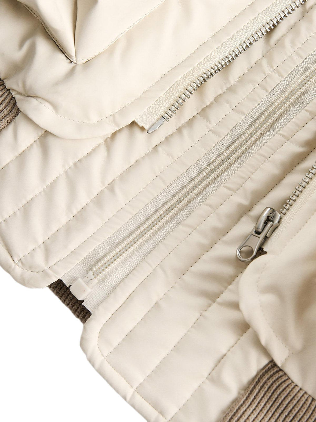 A detailed view of TALISHKO's puffer bomber jacket, focusing on the zipper and stitching.
