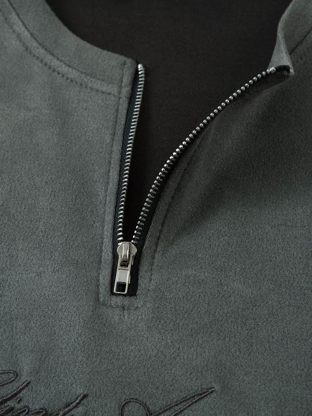 A detailed view of TALISHKO's suede quarter zip T-shirt, showcasing its sleek zipper and texture.