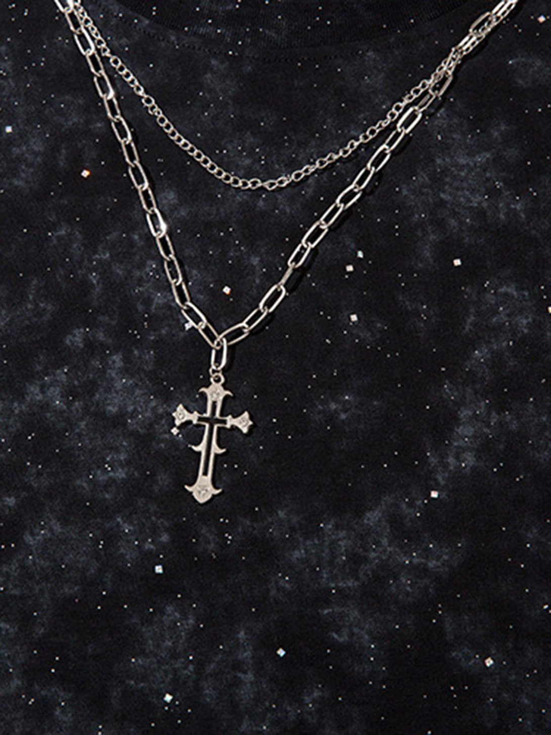 A detailed view of TALISHKO's retro rhinestone cross chain on a dark patterned background.