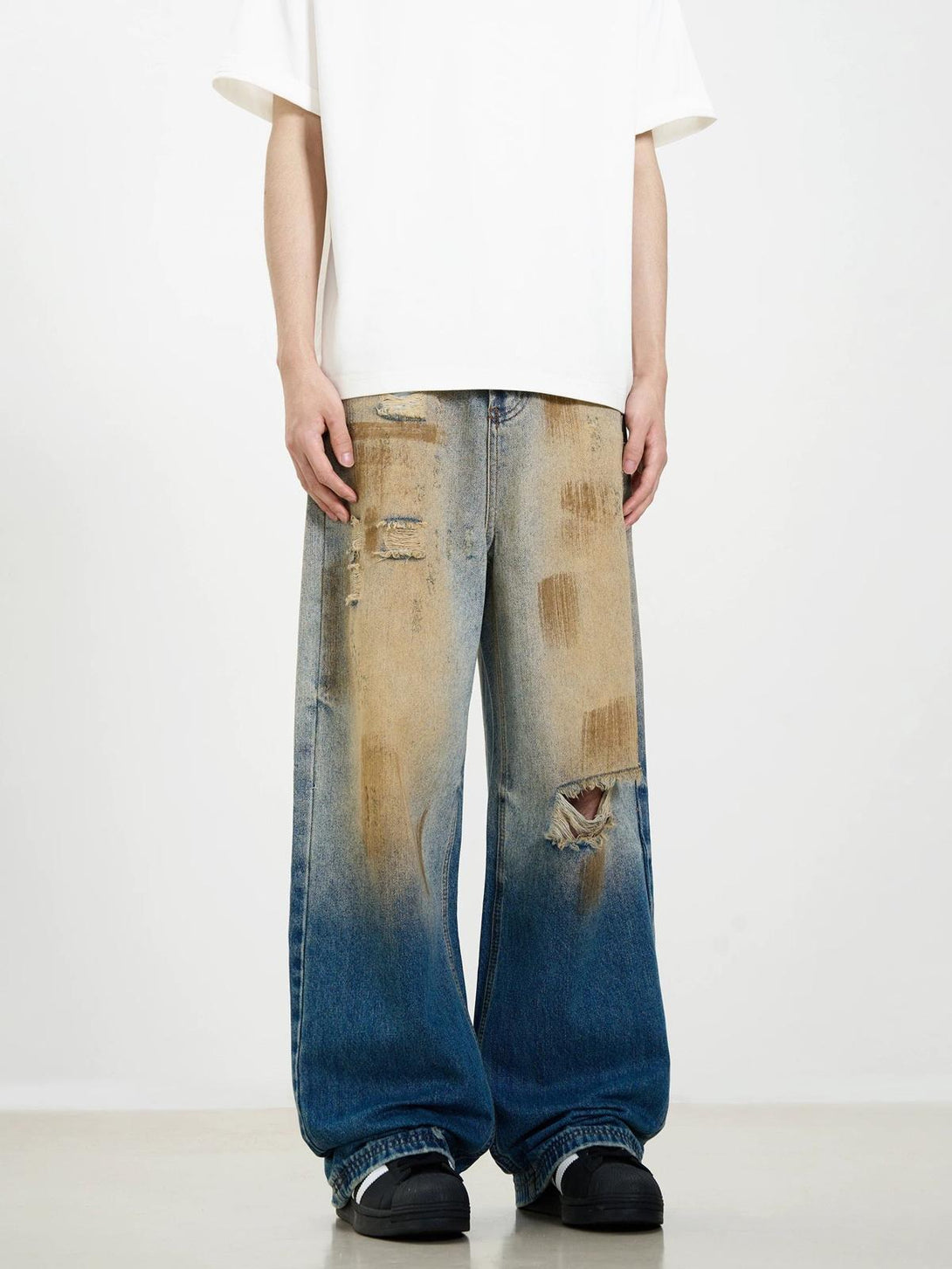 Model showcasing TALISHKO's ripped jeans with a washed patina and street-style flair.