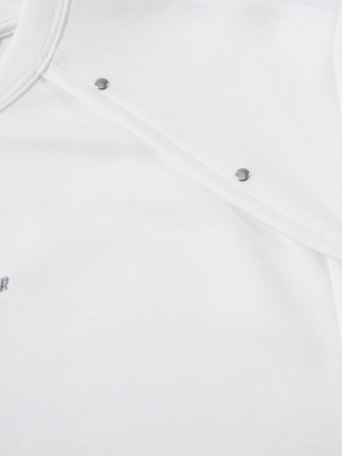 Detailed view of TALISHKO T-shirt showcasing rivet accents on smooth white fabric.