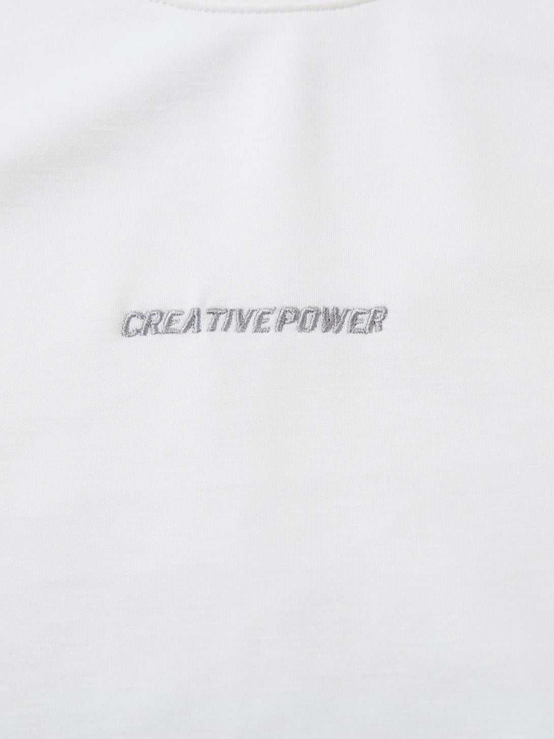 Intricate look at TALISHKO T-shirt embroidery, featuring "Creative Power" on soft white fabric.