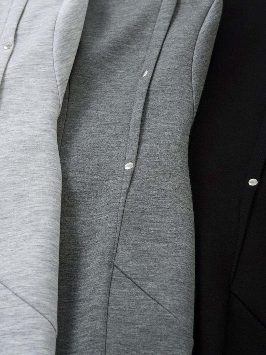 A close-up of gray pleated fabric with rivet details, highlighting TALISHKO's functional design.