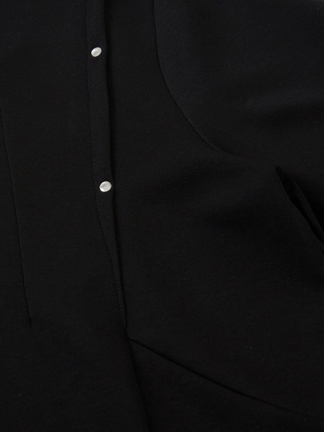 A close-up of black pleated fabric with rivet detail, highlighting TALISHKO's unique design.