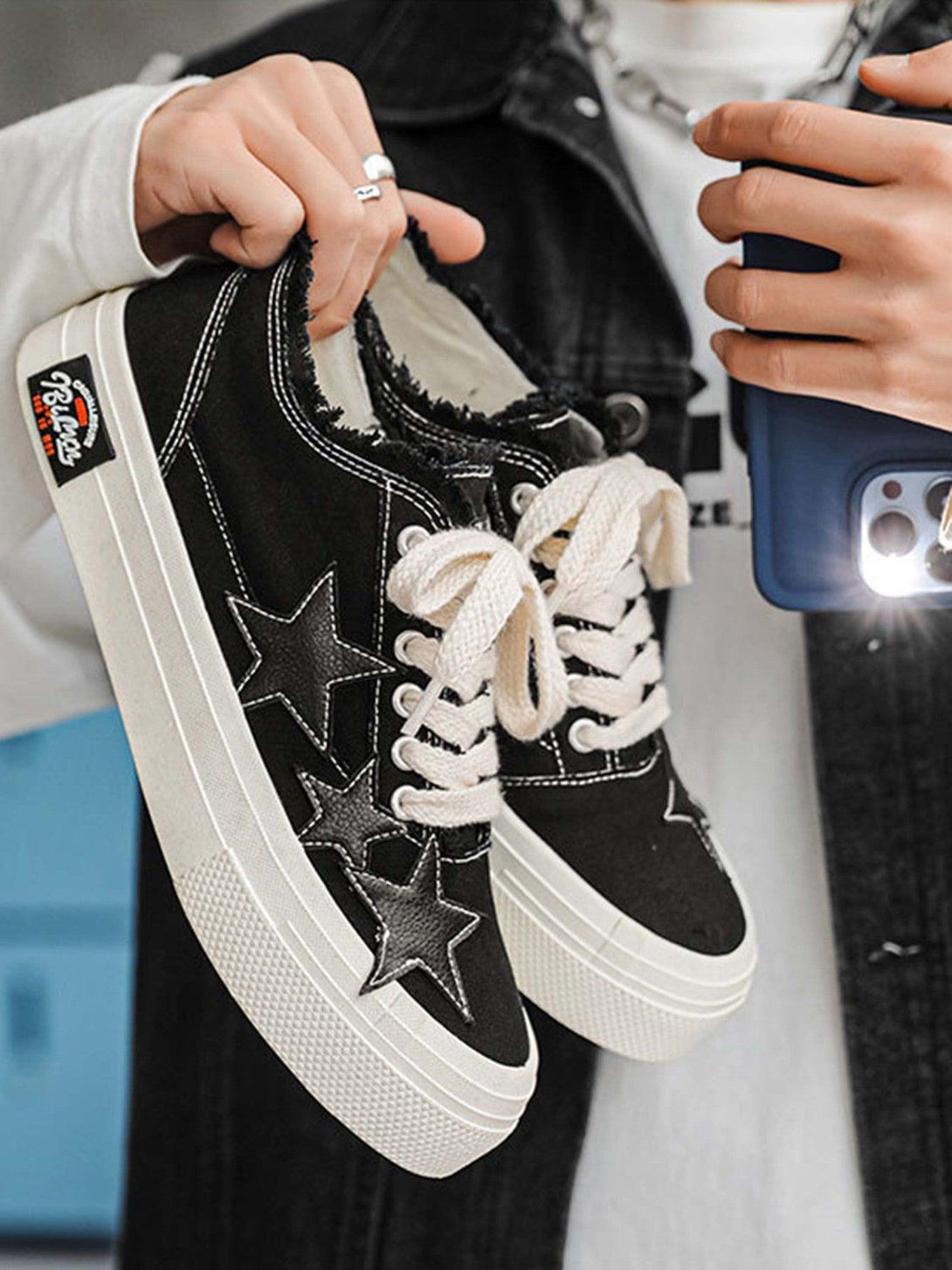 TALISHKO retro star canvas shoes in black with white laces, held casually for a stylish look.