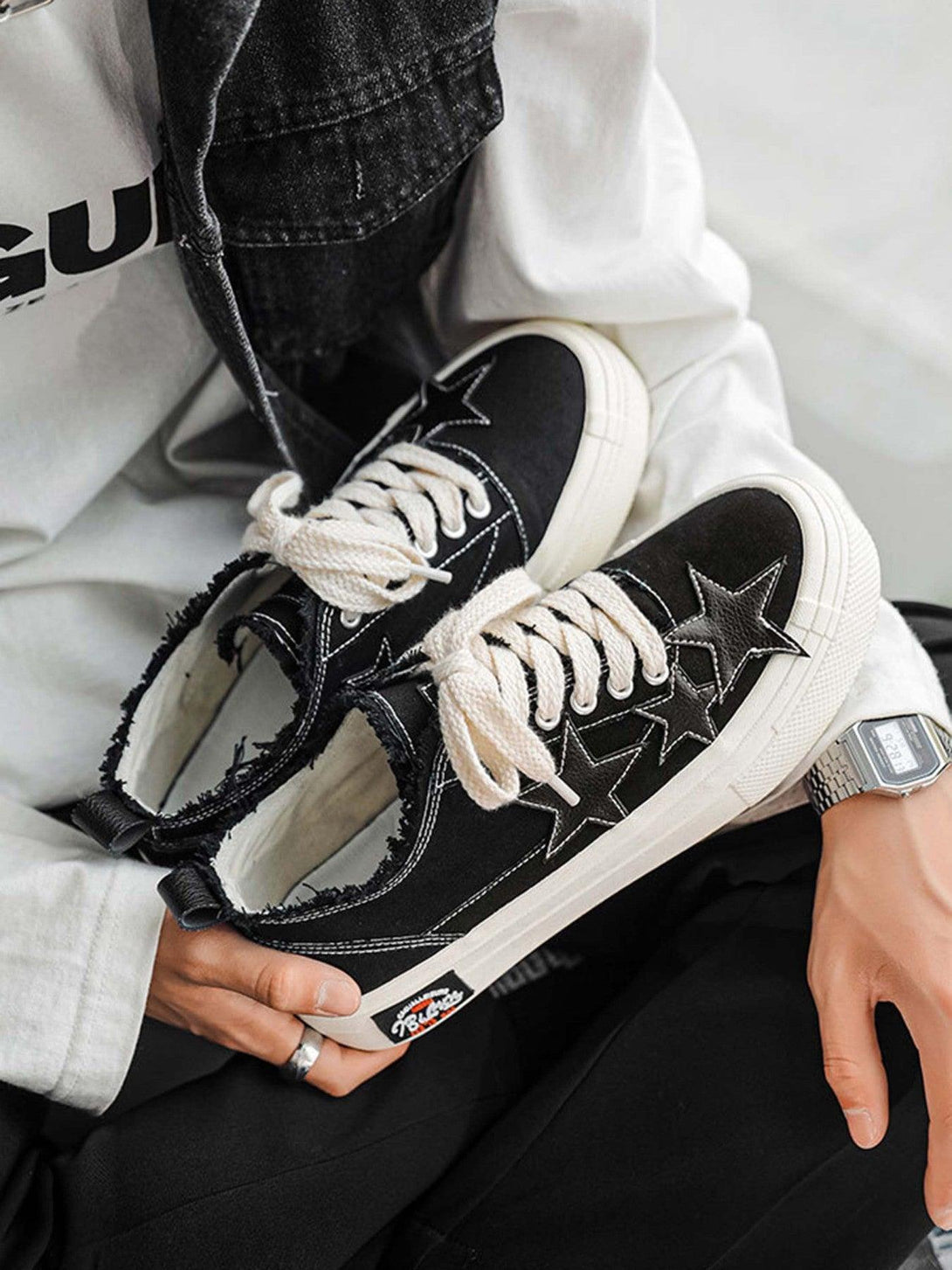 TALISHKO retro star canvas shoes in black with white laces, held casually for a chic look.