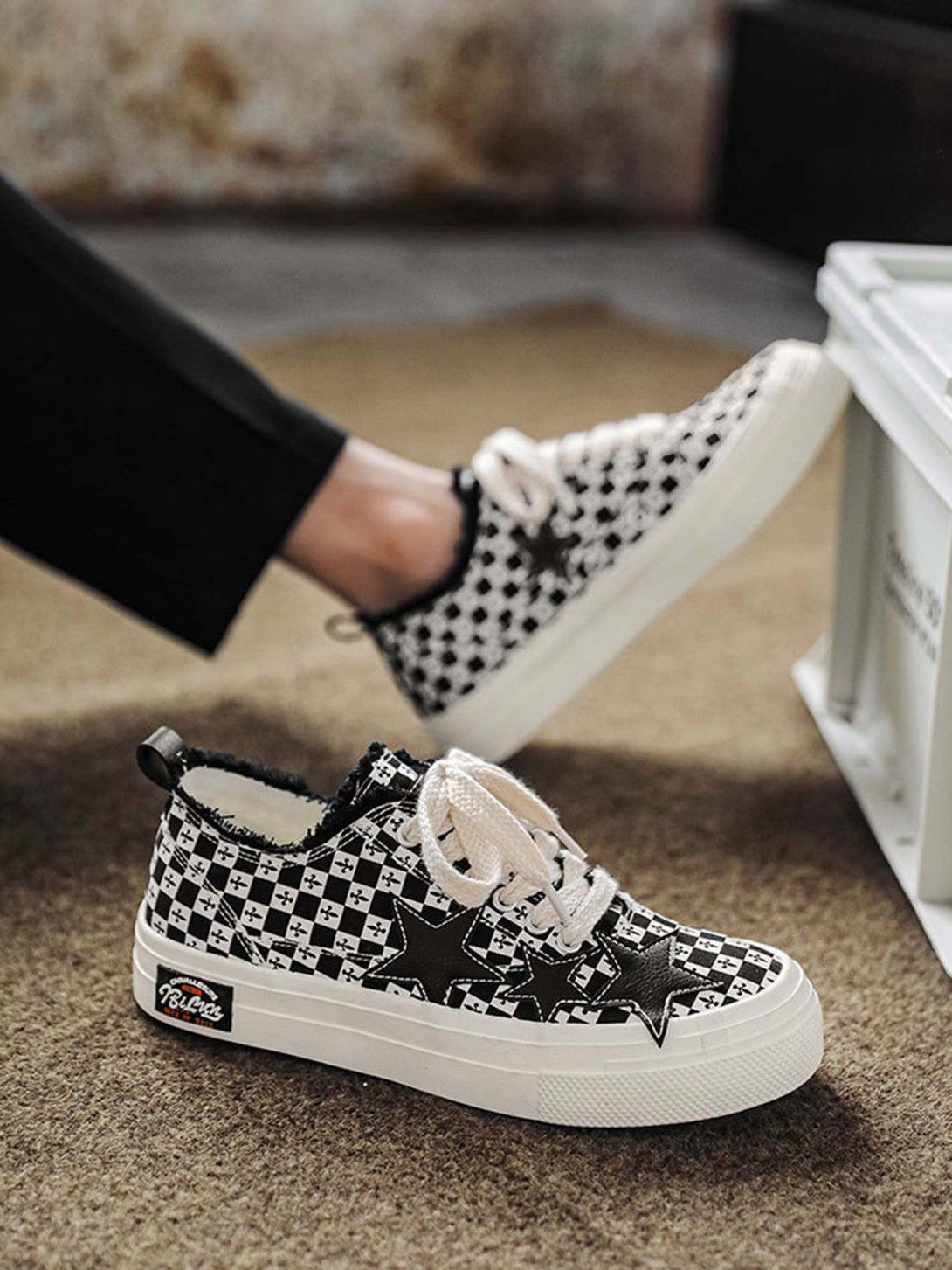 Black and white checkered canvas shoes with star design by TALISHKO, worn casually.