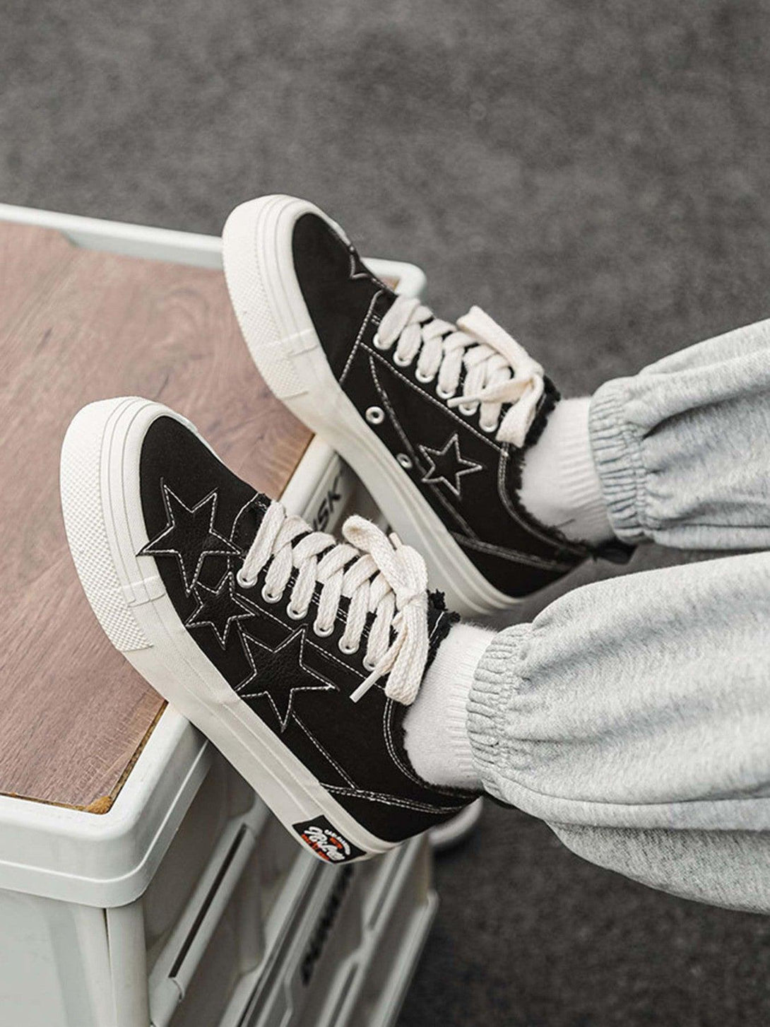 Black canvas shoes with star design by TALISHKO, paired with casual gray joggers.