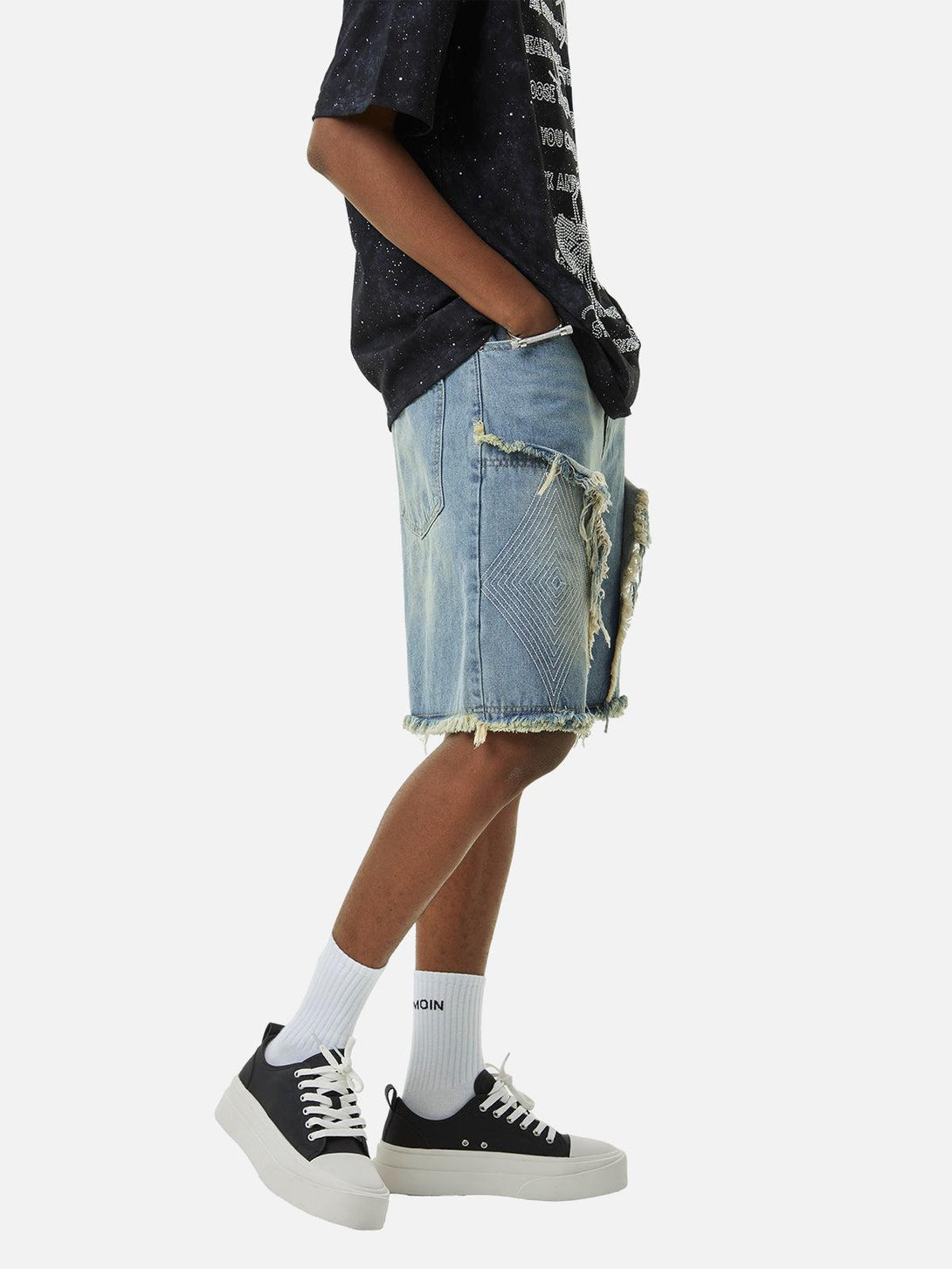 Model in TALISHKO denim shorts, side view highlighting frayed hem and retro embroidery.