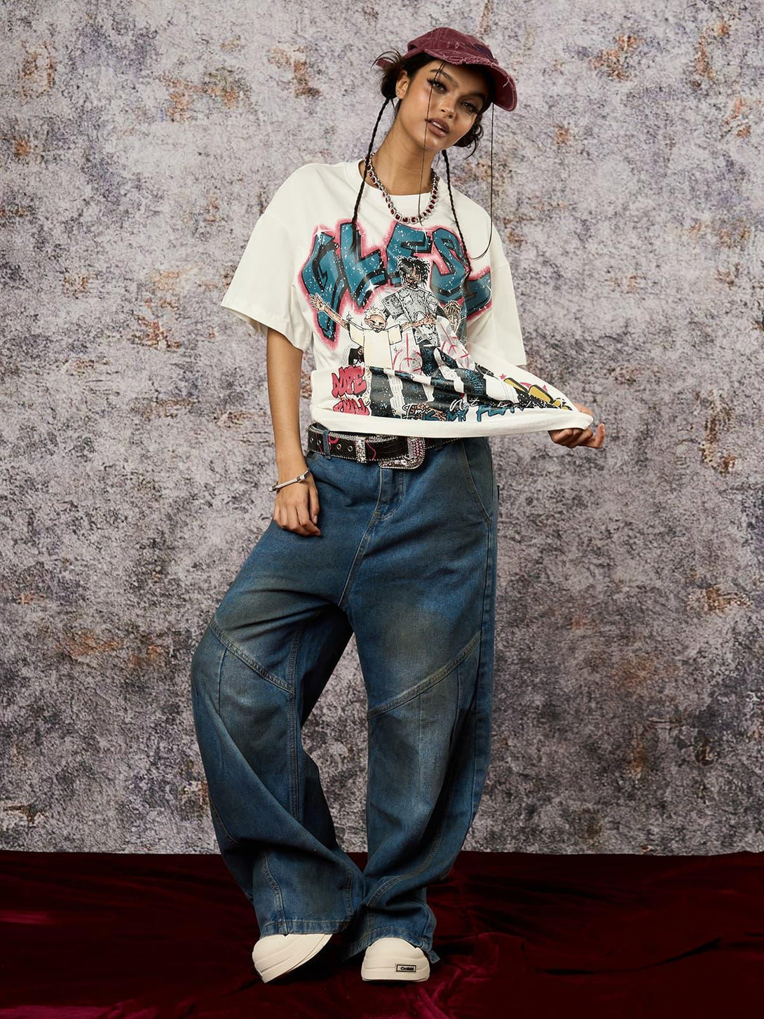Model wearing a TALISHKO Retro Street GLESA graphic T-shirt, paired with wide-leg jeans and a cap.