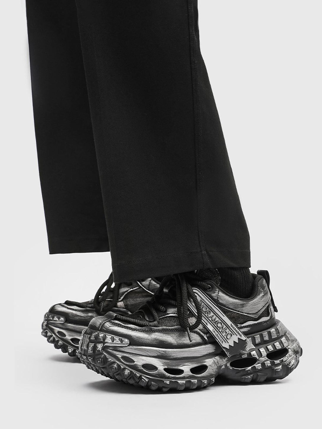 TALISHKO chunky sneakers with a rugged tire sole, paired with black trousers for a bold look.