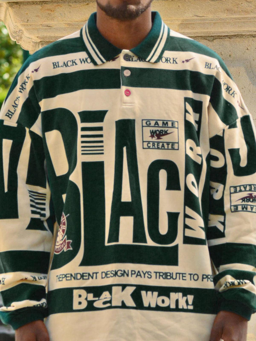 Model in a TALISHKO retro typography polo tee, featuring bold graphic text and green accents.