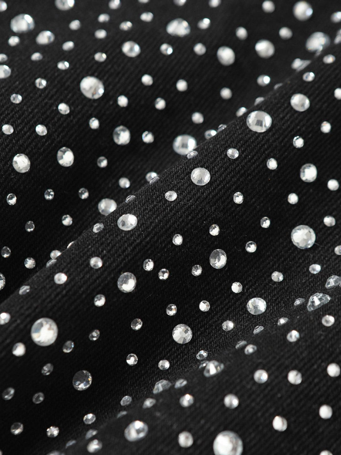 Sparkling rhinestones on TALISHKO denim shorts fabric, highlighting intricate design details.