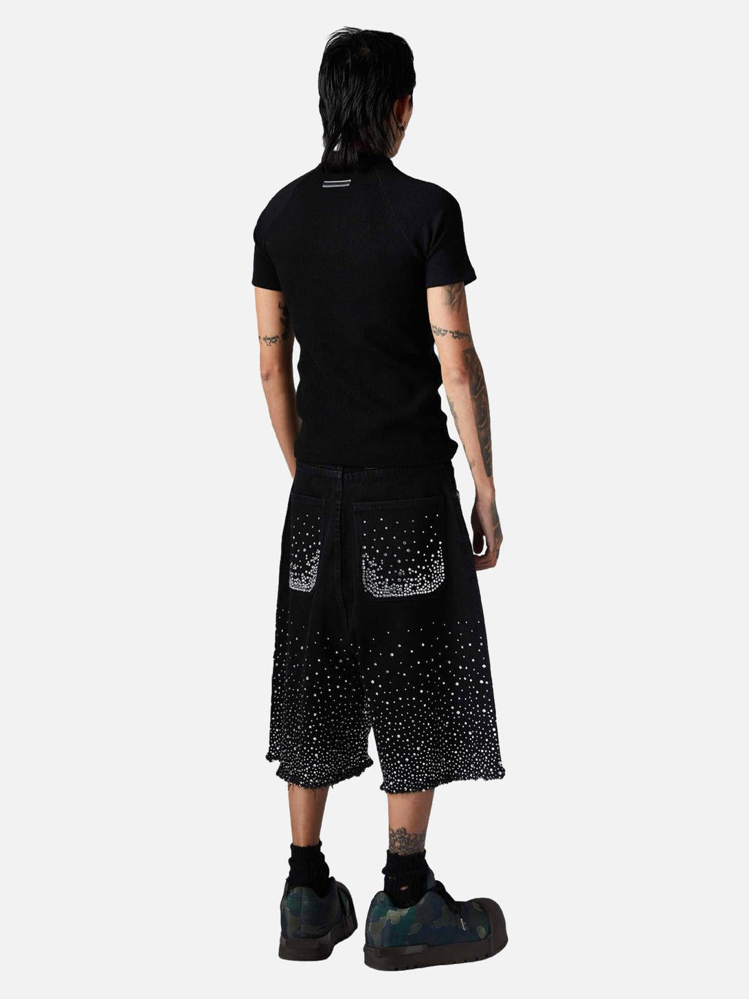 Model in TALISHKO denim shorts, rhinestone-studded with raw edges, from a back view.