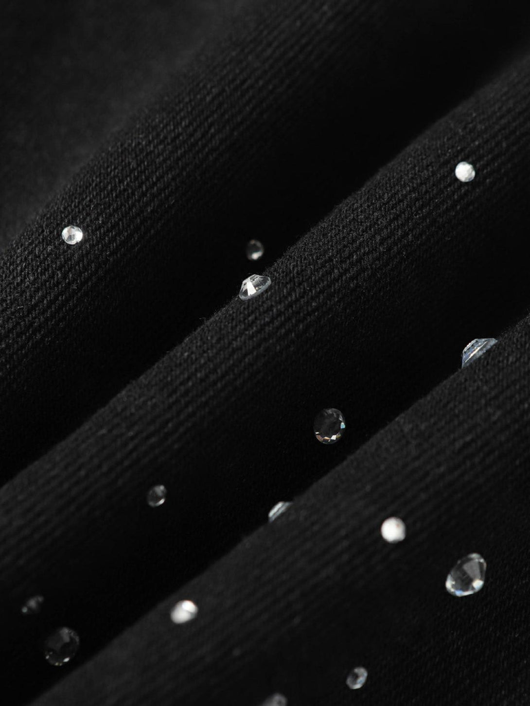 Intricate look at TALISHKO denim fabric with sparkling rhinestones, highlighting chic detail.