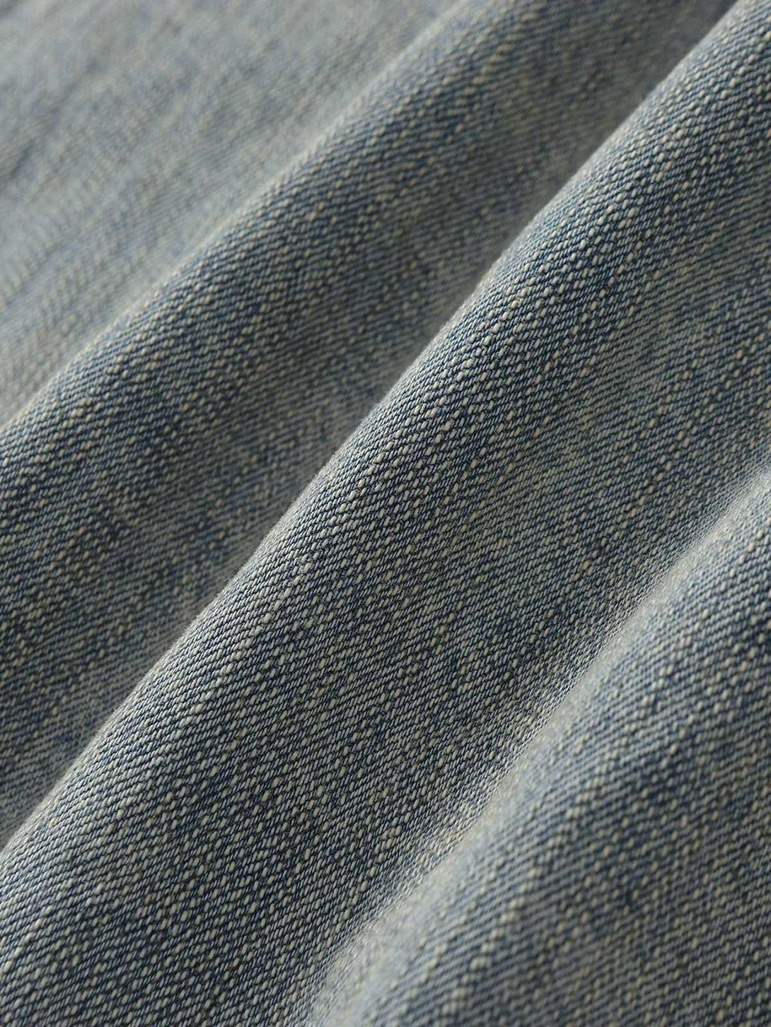 Zoomed-in texture of TALISHKO's retro washed denim jacket showcasing detailed fabric weave.