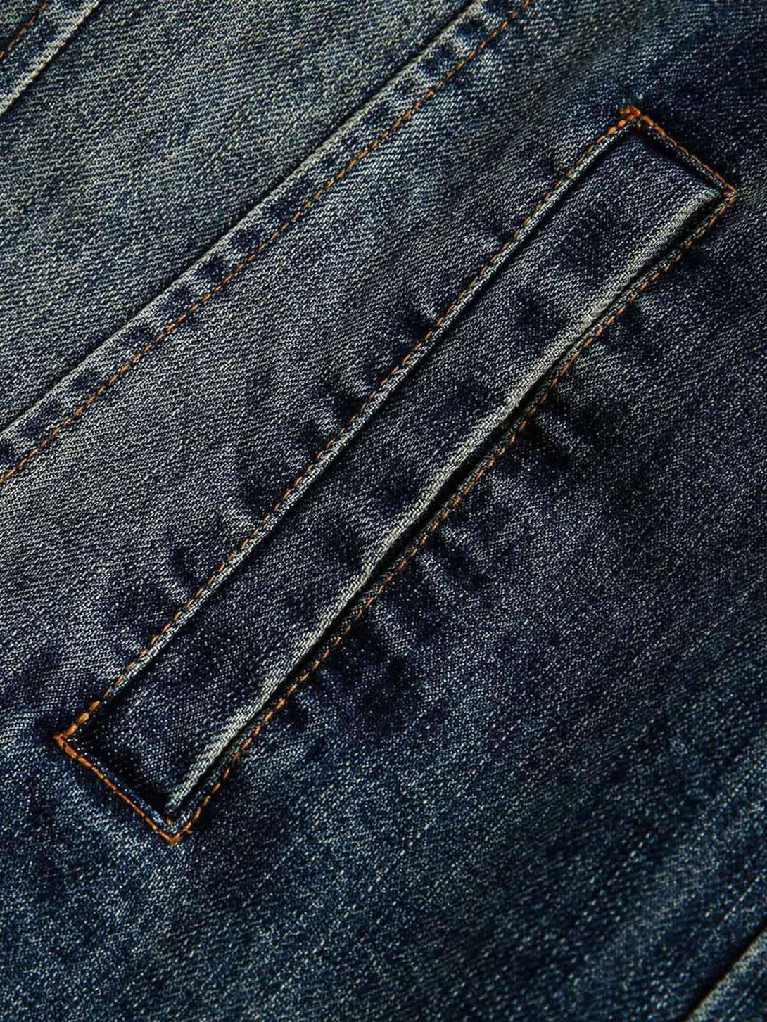 Zoomed-in texture of TALISHKO's retro washed denim jacket pocket detail and stitching.