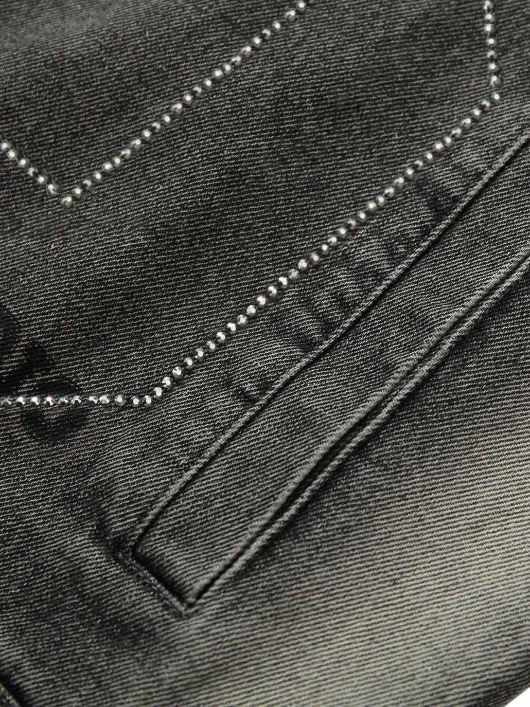 Intricate detail of TALISHKO's denim vest, highlighting rivet accents and texture.