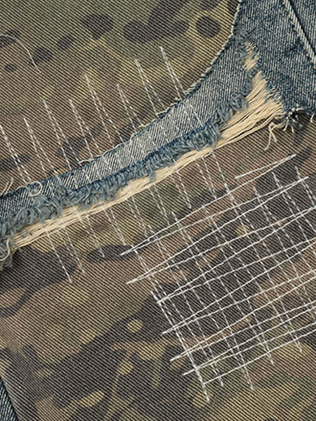 Intricate look at TALISHKO's ripped denim and camouflage patchwork on baggy jeans.