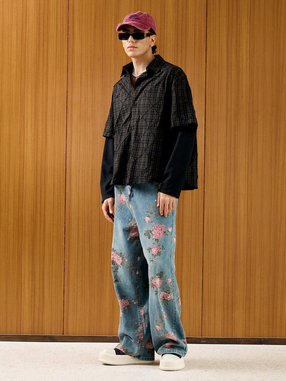 Model styled in layered black shirt and floral jeans with a red denim cap by TALISHKO.