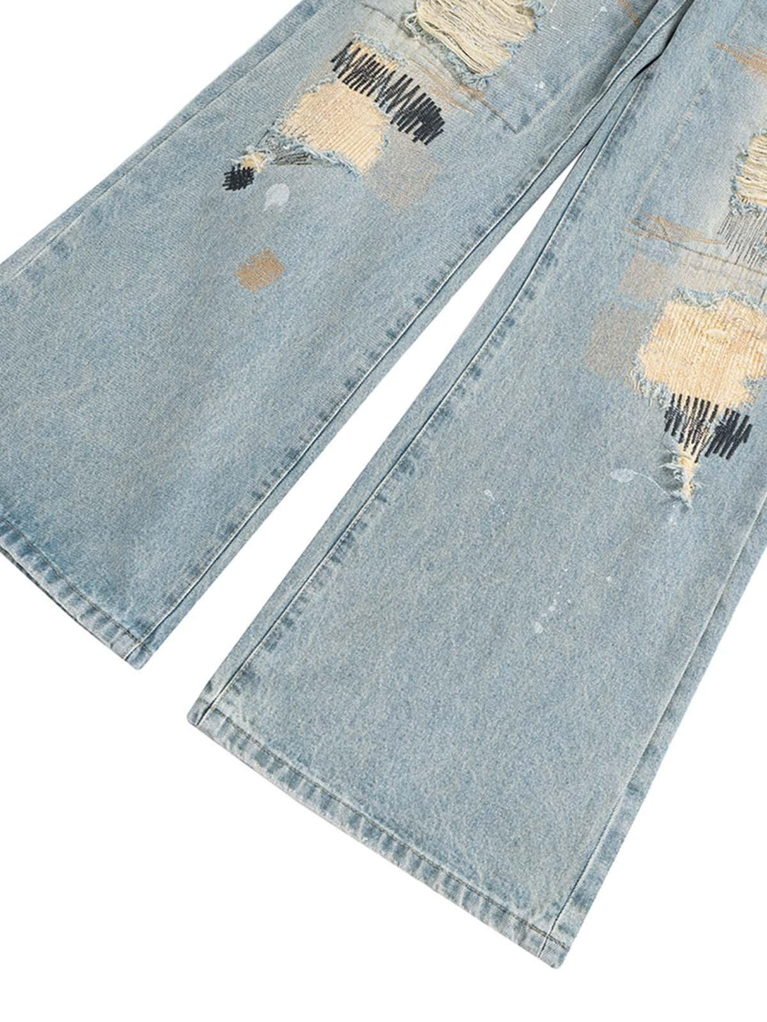 A detailed view of TALISHKO's distressed baggy flare jeans, highlighting unique patchwork.