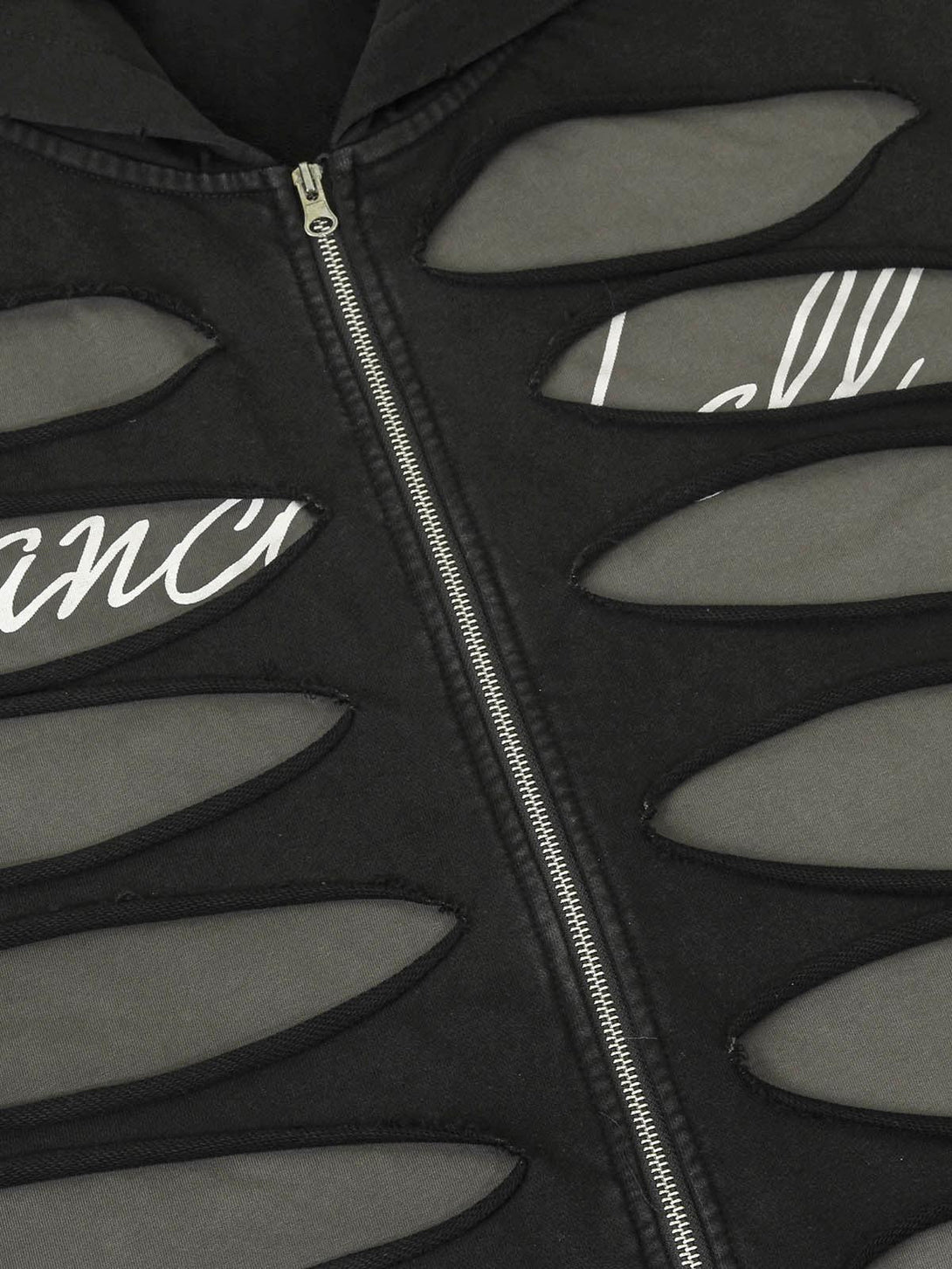Ripped detailing on a black zip-up jacket by TALISHKO, highlighting unique design features.