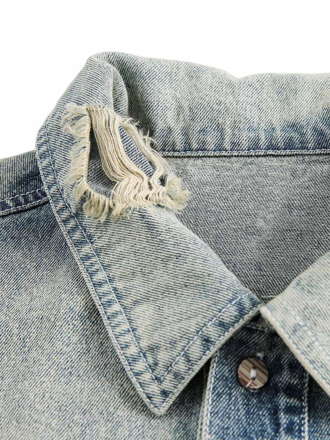 A close-up of TALISHKO's denim shirt collar, highlighting ripped detailing and faded texture.