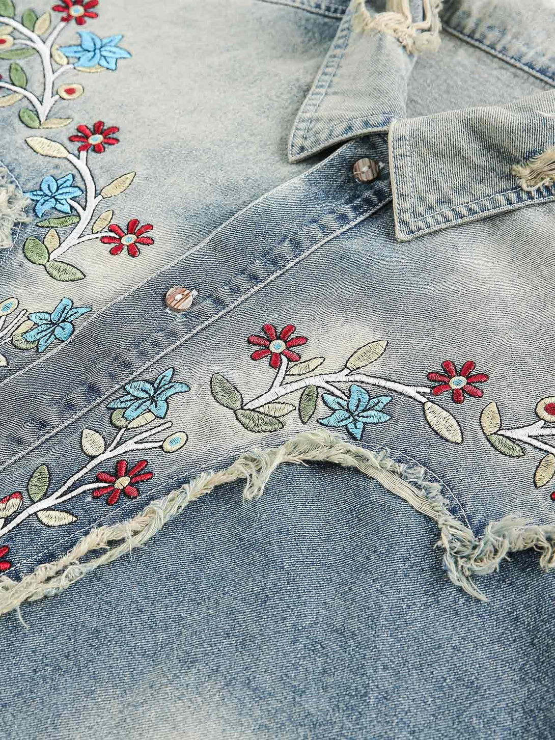 Intricate look at floral embroidery and distressed hem on TALISHKO's denim shirt.