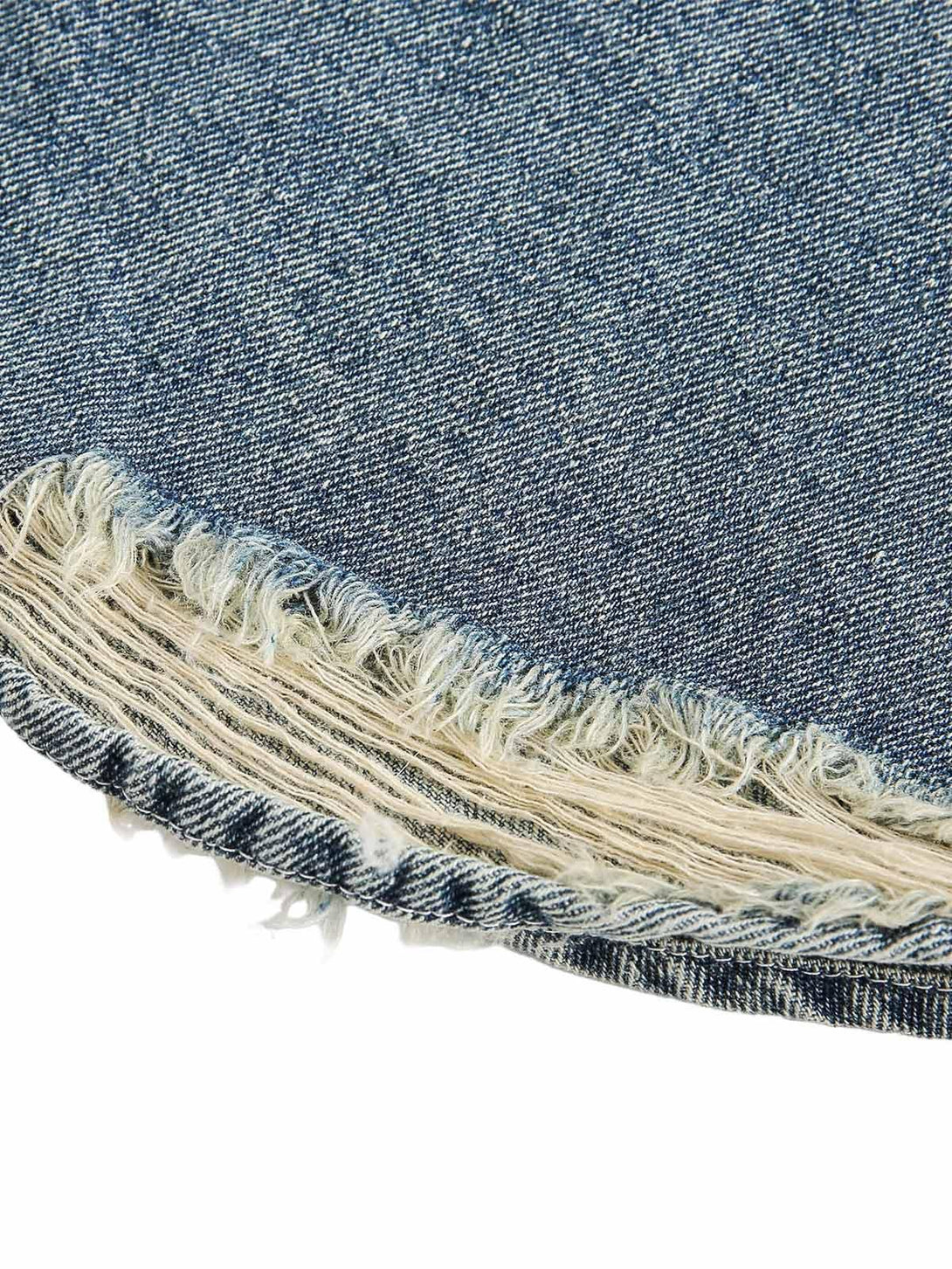Frayed edge detail on TALISHKO's denim shirt, showcasing its unique distressed texture.