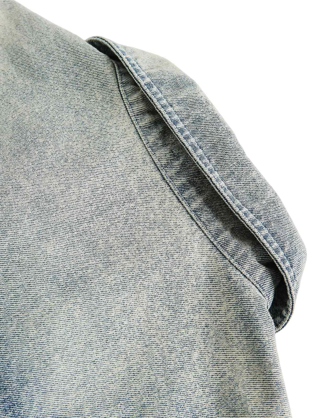 Detailed fabric and stitching on TALISHKO's denim shirt, emphasizing its faded texture.