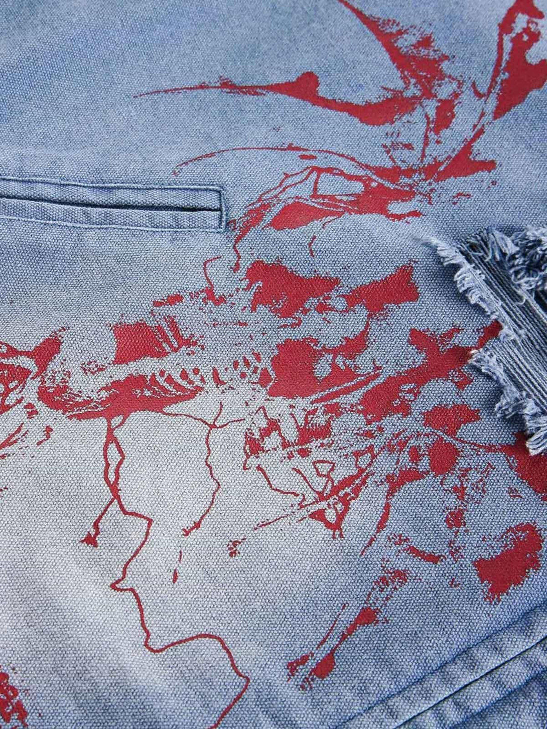A tight crop showcasing the red graffiti design and texture on a TALISHKO denim jacket.