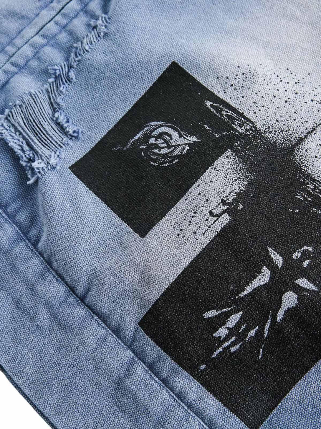 Zoomed-in view of a TALISHKO denim jacket's graffiti design and distressed fabric detail.