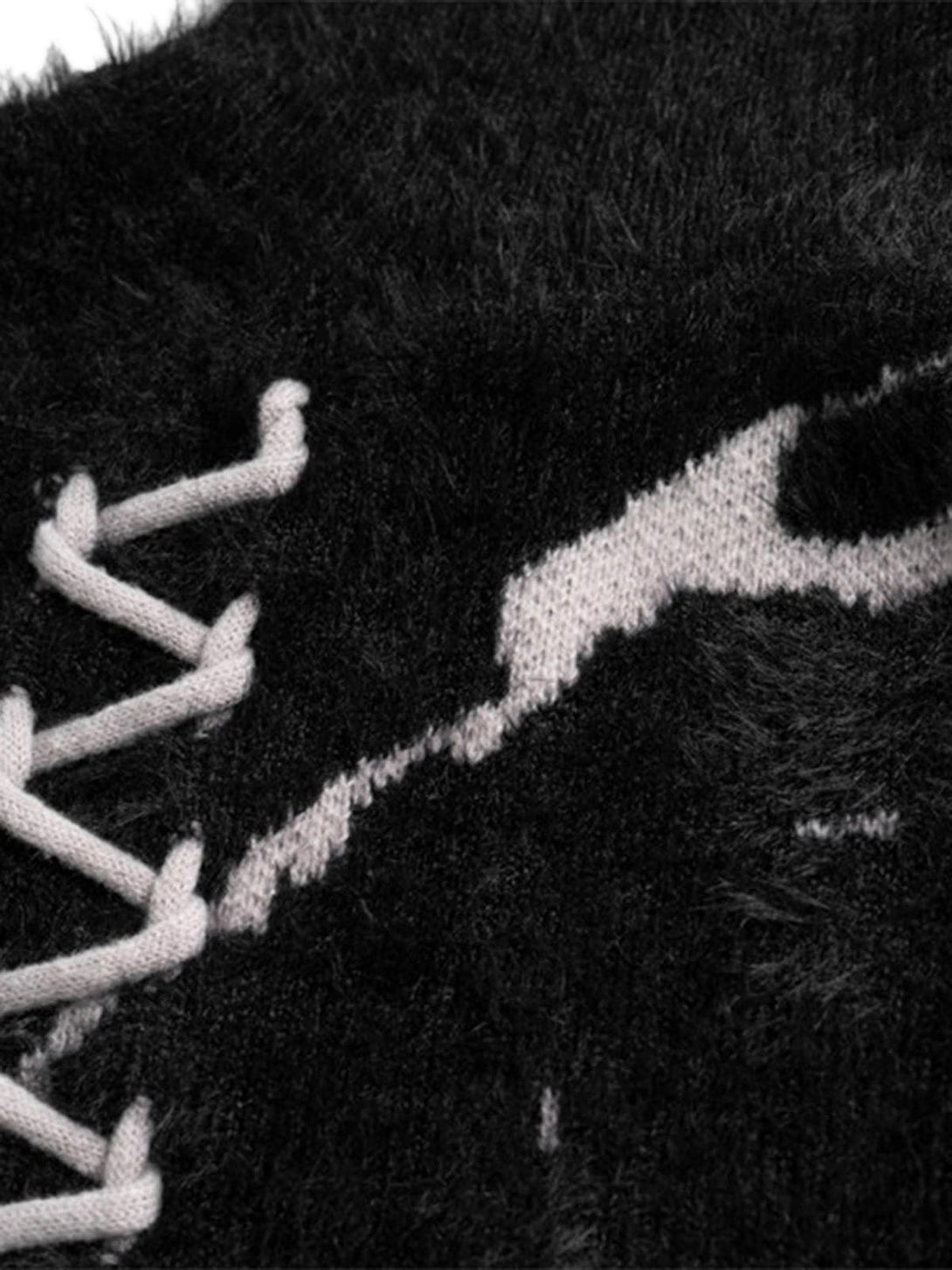 A tight crop highlighting the texture and lace-up detail of TALISHKO's ripped knit sweater.